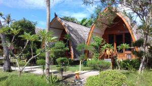 a house with a triangular roof with a fire hydrant in front at We'Be Cottages in Gili Meno