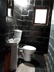 a bathroom with a toilet and a sink and a window at Amanzi Empilo Bungalow in Rhodes