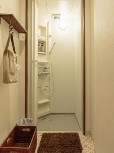 y baño con ducha y puerta de cristal. en J-Hoppers Hiroshima Guesthouse en Hiroshima