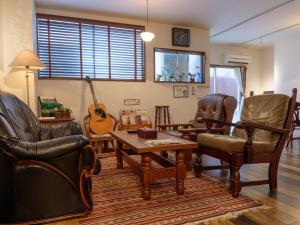 Una sala de estar llena de muebles y una guitarra. en J-Hoppers Hiroshima Guesthouse, en Hiroshima