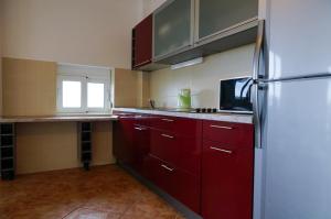 a kitchen with red cabinets and a refrigerator at Apart Hotel Forte Roses Montenegro KO Buljarica in Petrovac na Moru