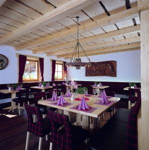 un comedor con mesas con servilletas y sillas moradas en Apartments Restaurant Rusctlea, en Selva di Val Gardena