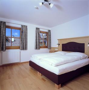 ein Schlafzimmer mit einem großen Bett und zwei Fenstern in der Unterkunft Apartments Restaurant Rusctlea in Wolkenstein in Gröden