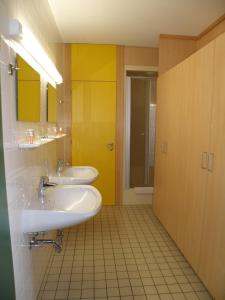 baño con 2 lavabos y pared amarilla en Hotel Sommerhaus, en Bad Leonfelden