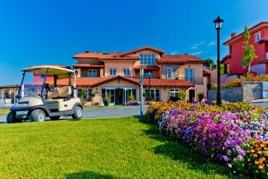 un carro de golf estacionado frente a una casa con flores en Villa Carolina Resort, en Castelletto d'Orba