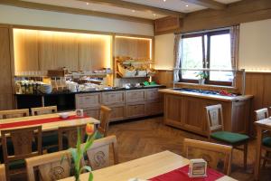un ristorante con cucina con mobili e tavoli in legno di Hotel-Gasthof Kramerwirt a Irschenberg Altre 26 foto