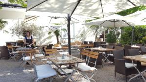 een vrouw in een restaurant met tafels en parasols bij Wildenauer's in Biedermannsdorf