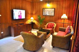 a living room with wicker chairs and a flat screen tv at Baan Khun Nang Colonial Residence in Mae Nam