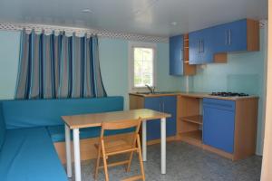 cocina con armarios azules y mesa de madera en Camping La Aventura Playa, en Daimuz