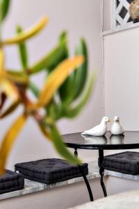 two white birds sitting on a table next to a plant at Aleka's Rooms in Tinos