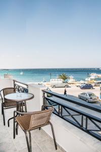 uma varanda com mesas e cadeiras e a praia em Aleka's Rooms em Tinos Town