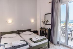 a bedroom with two beds and a balcony at Aleka's Rooms in Tinos