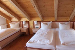 two beds in a room with wooden ceilings at Hotel-Gasthof Kramerwirt in Irschenberg