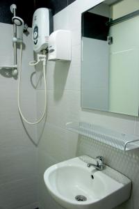 Baño blanco con lavabo y espejo en Maple Inn, en Kuala Lumpur