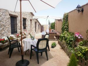 a patio with a table and chairs and an umbrella at Camino del Prado in Santa María la Real de Nieva