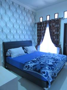 a bedroom with a blue bed with a blue comforter and a window at Villa Zam Zam Syariah in Puncak