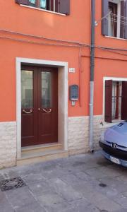 eine Tür in einem orangenen Gebäude mit einem Auto vor der Tür in der Unterkunft Casa Lorella in Chioggia