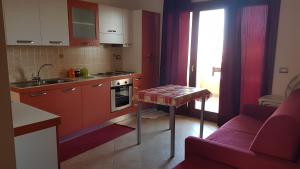 カステルサルドにあるResidenza Lentiscoの赤いキャビネット、テーブル、ソファ付きのキッチンが備わります。