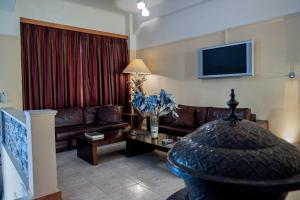 a living room with a couch and a tv at Plaza Hotel in Loutraki