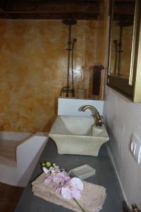 a bathroom with a sink and flowers on a counter at Casa Rural "La Molina" in Máguez