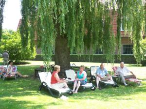 a group of people sitting in chairs under a tree at NordWest-Hotel Amsterdam in Bad Zwischenahn
