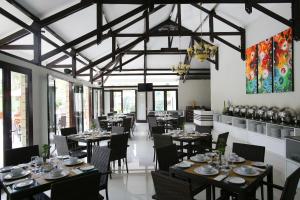 a dining room with tables and chairs and windows at Samara Resort in Batu