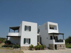 Una gran casa blanca con persianas verdes. en Myrto Apartments en Kálamos Kythira