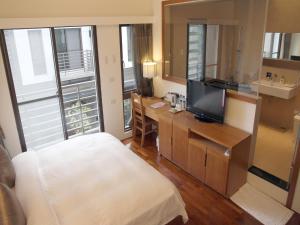 a hotel room with a bed and a desk with a television at Peace Area Hot Spring Hotel in Jiaoxi