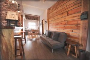 ein Wohnzimmer mit Sofa und einer Holzwand in der Unterkunft Pine Breeze Cottages in Baguio City