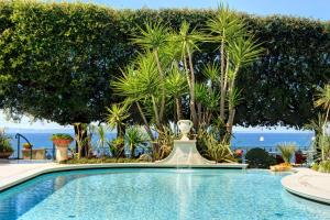 a swimming pool with a fountain in front of trees at Grand Hotel Ambasciatori in Sorrento