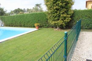 
a grassy area with a fence and a tennis court at Spacious Villa in Azeitão (with private pool) in Azeitao
