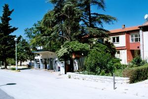 a house with a tree on the side of a street at Hostel Amfora in Fažana
