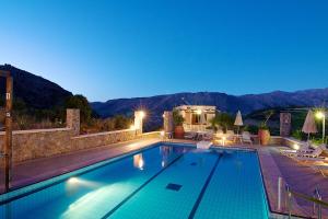 a swimming pool at night with a house and mountains at Elia Meronas in Méronas