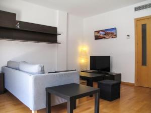 a living room with a white couch and a tv at Goleta Almeria in Almería