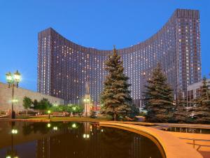 a large building with christmas trees in front of a pond at Cosmos Club Hotel in Moscow