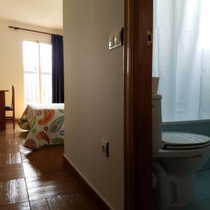 a bathroom with a toilet and a bed with a window at Hotel Condes de Buñol in Buñol