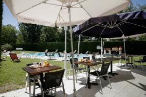 - deux tables et des chaises sous des parasols à côté d'une piscine dans l'établissement The Originals City, Hôtel Le Sextant, Toulouse Sud, à Labège