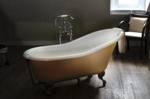 a bath tub with a faucet in a bathroom at Gwesty'r Marine Hotel & Spa in Aberystwyth