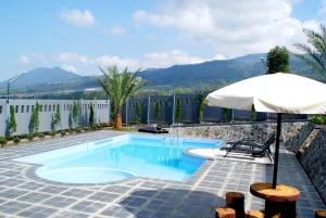 einen Pool mit Sonnenschirm, Tisch und Stühlen in der Unterkunft Osmond Villa Resort in Lembang
