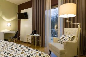um quarto de hotel com uma cama e uma cadeira e uma janela em Alva Valley Hotel em Oliveira do Hospital