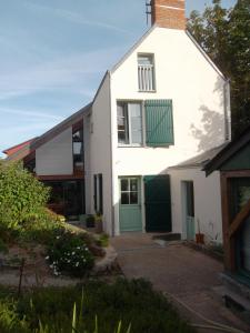 una casa blanca con una puerta verde en Chambres des Noels, en Faye-dʼAnjou