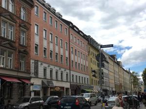 uma movimentada rua da cidade com carros estacionados na rua em Hotel Hauser an der Universität em Munique