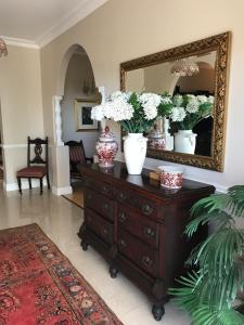 a room with a dresser with vases and a mirror at Edens Guest House in Durban