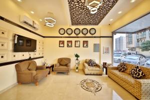 a living room with couches and chairs and a tv at Midtown Furnished Apartments in Ajman 