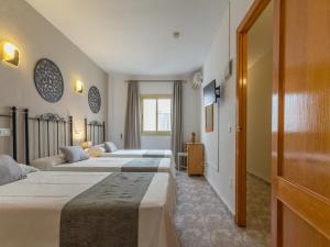 - une rangée de 4 lits dans une chambre d'hôtel dans l'établissement Hostal Dinamarca, à Sant Antoni de Portmany