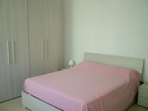 una camera da letto con un letto rosa e armadi bianchi di San Teodoro Apartment a Mestre