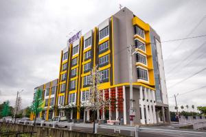 un bâtiment jaune et blanc sur le côté d'une rue dans l'établissement OMG Hotel, à Simpang Ampat