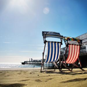 two chairs sitting on the beach near a pier at The Sandown - Seafront, Sandown, Isle of Wight - CAR FERRY TICKET from 109 Pounds in Sandown