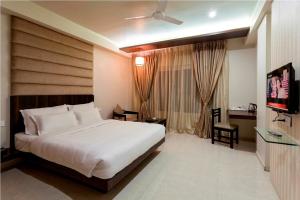 a hotel room with a bed and a television at Hotel Rasika in Kolhapur