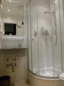 a bathroom with a shower and a tub and a sink at Hotel Hauser an der Universität in Munich